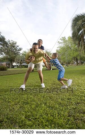 Portrait of a father playing with their children at park View Large Photo Image Stock Photo - Portrait of a father playing with their children at park. Fotosearch