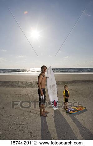 Portrait of a father with his son standing by surfboard at the beach View Large Photo Image Stock Image - Portrait of a father with his son standing by surfboard at the beach. Fotosearch