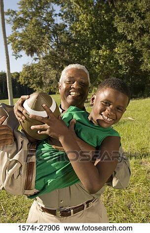 Stock Photograph - Portrait of a father with his son holding football at forest. Fotosearch