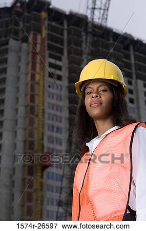 Portrait of a female architect standing in front of a building under construction View Large Photo Image Stock Photo - Portrait of a female architect standing in front of a building under construction. Fotosearch