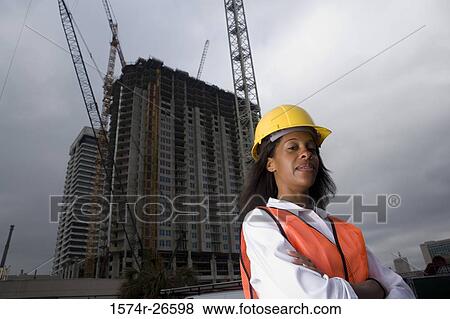 Portrait of a female architect standing in front of a building under construction View Large Photo Image Stock Photo - Portrait of a female architect standing in front of a building under construction. Fotosearch