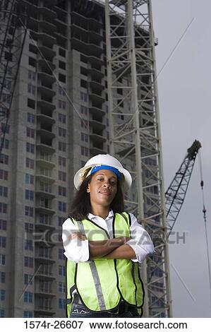 Portrait of a female architect standing in front of a building under construction View Large Photo Image Stock Photo - Portrait of a female architect standing in front of a building under construction. Fotosearch
