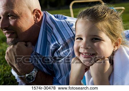 Portrait of a girl lying by her father and smiling View Large Photo Image Stock Photo - Portrait of a girl lying by her father and smiling. Fotosearch