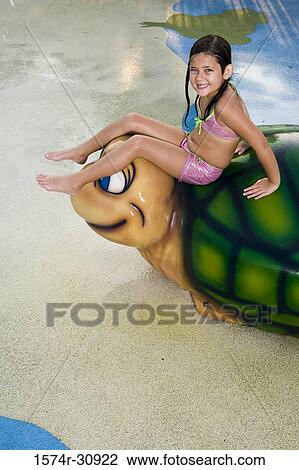 Stock Image - Portrait of a girl sitting on a tortoise sculpture. Fotosearch