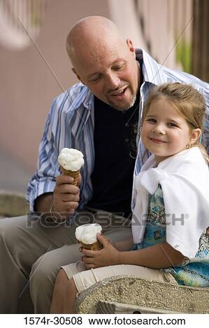 Portrait of a girl sitting with her father holding ice cream cones View Large Photo Image Stock Photo - Portrait of a girl sitting with her father holding ice cream cones. Fotosearch