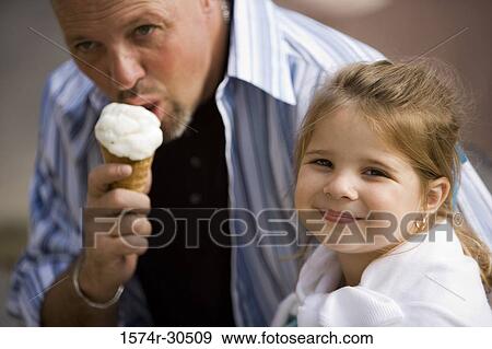 Portrait of a girl sitting with her father eating an ice cream cone View Large Photo Image Stock Photo - Portrait of a girl sitting with her father eating an ice cream cone. Fotosearch