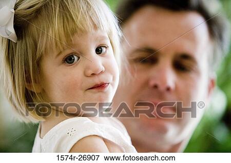 Stock Photo - Portrait of a girl with her father in the background. Fotosearch
