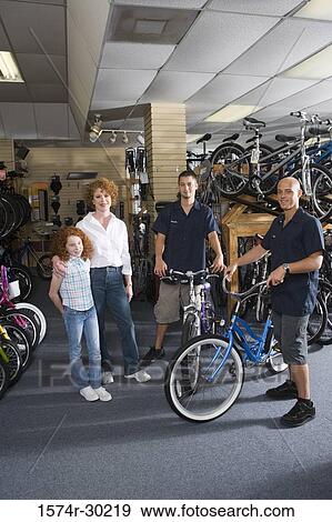 Portrait of a girl with her mother while men holding bicycles in a bicycle shop View Large Photo Image Stock Photo - Portrait of a girl with her mother while men holding bicycles in a bicycle shop. Fotosearch