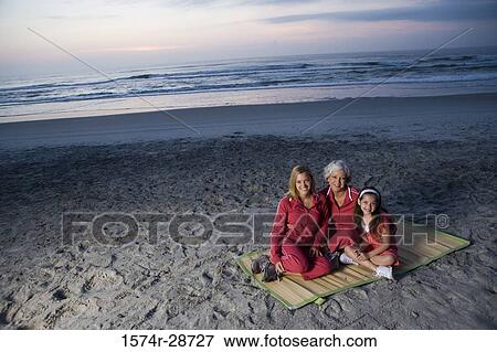 Portrait of a grandmother with her daughter and granddaughter sitting on a mat at the beach View Large Photo Image Stock Photo - Portrait of a grandmother with her daughter and granddaughter sitting on a mat at the beach. Fotosearch