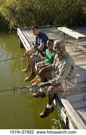 Stock Image - Portrait of a man fishing with his son and friend on jetty. Fotosearch