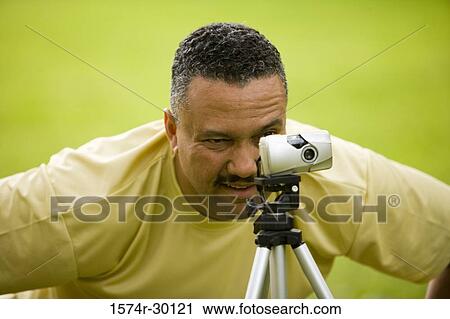 Portrait of a man photographing with camera and tripod at park View Large Photo Image Stock Image - Portrait of a man photographing with camera and tripod at park. Fotosearch