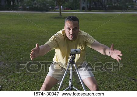Portrait of a man photographing with camera and tripod at park View Large Photo Image Stock Photo - Portrait of a man photographing with camera and tripod at park. Fotosearch