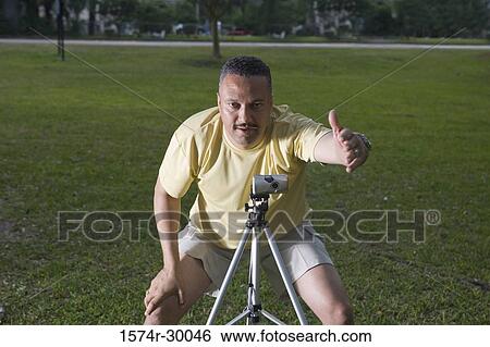 Portrait of a man photographing with camera and tripod at park View Large Photo Image Stock Photograph - Portrait of a man photographing with camera and tripod at park. Fotosearch