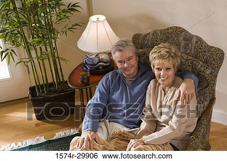 Stock Photograph - Portrait of a mature couple sitting with their arms around. Fotosearch