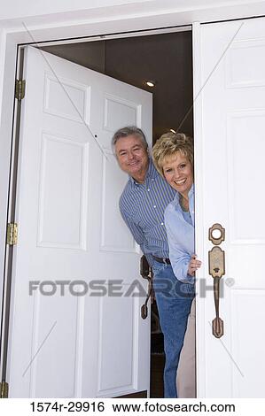 Portrait of a mature couple standing together by a door and smiling View Large Photo Image Stock Photograph - Portrait of a mature couple standing together by a door and smiling. Fotosearch
