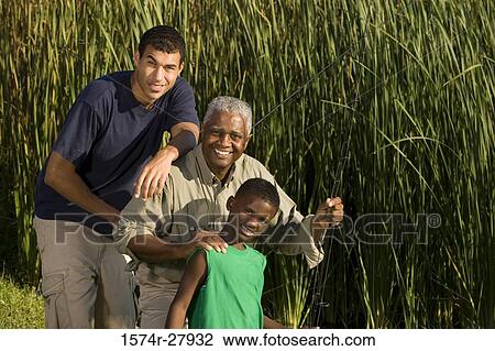 Stock Image - Portrait of a mature man with his son and friend smiling at forest. Fotosearch