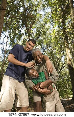 Portrait of a mature man with his son and friend smiling at forest View Large Photo Image Stock Photo - Portrait of a mature man with his son and friend smiling at forest. Fotosearch