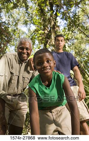 Portrait of a mature man with his son and friend smiling at forest View Large Photo Image Stock Photo - Portrait of a mature man with his son and friend smiling at forest. Fotosearch