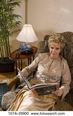 Portrait of a mature woman sitting on a chair holding a book View Large Photo Image Stock Image - Portrait of a mature woman sitting on a chair holding a book. Fotosearch