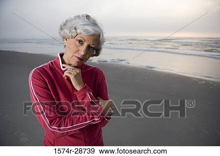 Stock Photo - Portrait of a mature woman standing at the beach. Fotosearch