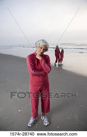 Portrait of a mature woman standing while other walking at the beach View Large Photo Image Stock Image - Portrait of a mature woman standing while other walking at the beach. Fotosearch