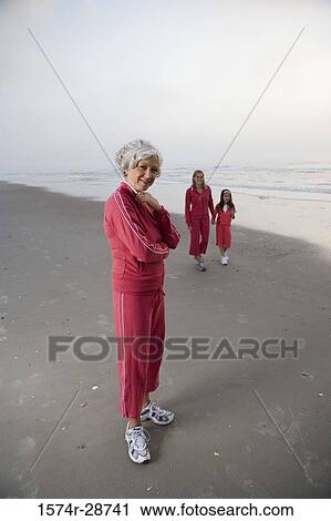 Portrait of a mature woman standing while other walking at the beach View Large Photo Image Stock Image - Portrait of a mature woman standing while other walking at the beach. Fotosearch