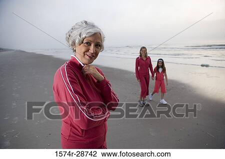 Portrait of a mature woman standing while other walking at the beach View Large Photo Image Stock Image - Portrait of a mature woman standing while other walking at the beach. Fotosearch