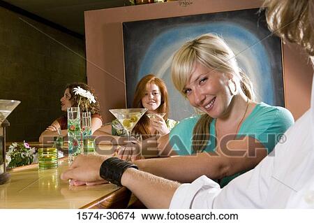Picture - Portrait of a mature woman with daughters by bar counter. Fotosearch