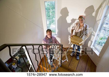 Portrait of a mid adult couple carrying chairs on the staircase View Large Photo Image Stock Photo - Portrait of a mid adult couple carrying chairs on the staircase. Fotosearch