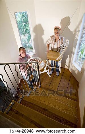 Portrait of a mid adult couple carrying chairs on the staircase View Large Photo Image Stock Photo - Portrait of a mid adult couple carrying chairs on the staircase. Fotosearch