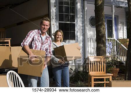 Picture - Portrait of a mid adult couple unloading chairs and cardboard boxes from the moving van. Fotosearch