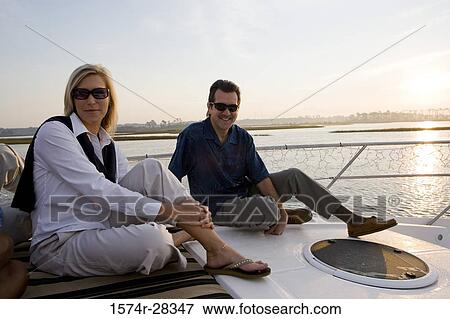 Portrait of a mid adult couple relaxing on the deck of a boat View Large Photo Image Stock Photo - Portrait of a mid adult couple relaxing on the deck of a boat. Fotosearch