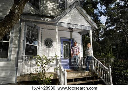 Portrait of a mid adult couple standing by house View Large Photo Image Stock Image - Portrait of a mid adult couple standing by house. Fotosearch