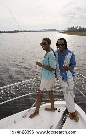 Portrait of a mid adult couple standing with glass of champagne at bow of a boat View Large Photo Image Stock Photograph - Portrait of a mid adult couple standing with glass of champagne at bow of a boat. Fotosearch
