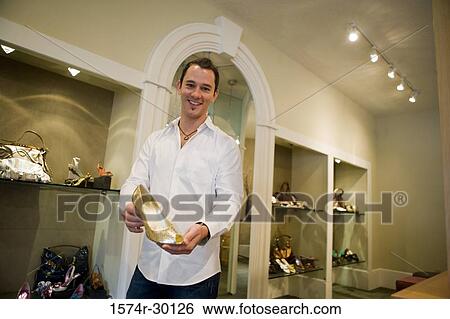 Portrait of a mid adult man showing woman's shoe in a store View Large Photo Image Stock Photograph - Portrait of a mid adult man showing woman's shoe in a store. Fotosearch