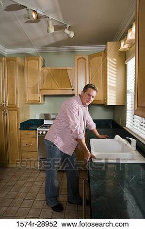 Portrait of a mid adult man standing by kitchen counter in the kitchen View Large Photo Image Stock Image - Portrait of a mid adult man standing by kitchen counter in the kitchen. Fotosearch