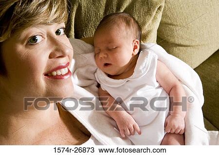 Stock Image - Portrait of a mid adult woman holding her baby in hands. Fotosearch