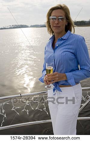 Portrait of a mid adult woman standing with glass of champagne View Large Photo Image Picture - Portrait of a mid adult woman standing with glass of champagne. Fotosearch