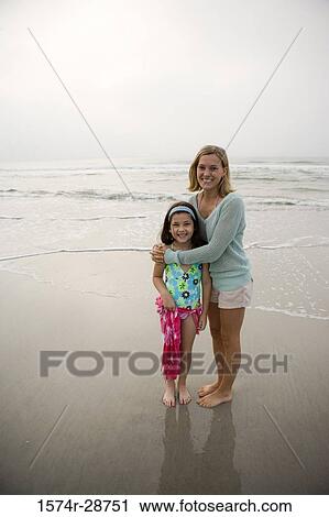 Stock Image - Portrait of a mother embracing her daughter at the beach. Fotosearch