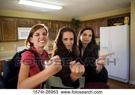 Stock Image - Portrait of a mother gesturing with her daughters in kitchen. Fotosearch