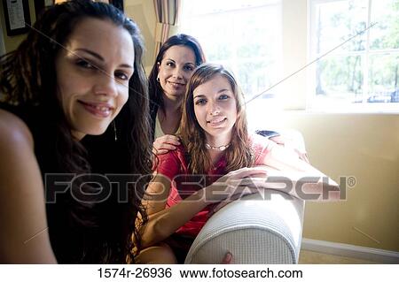 Portrait of a mother smiling with her daughters in the living room View Large Photo Image Stock Photograph - Portrait of a mother smiling with her daughters in the living room. Fotosearch