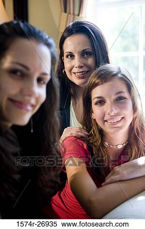 Stock Photography - Portrait of a mother smiling with her daughters in the living room. Fotosearch