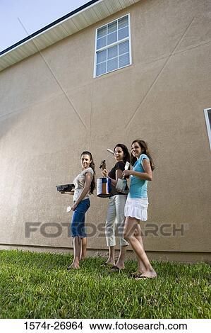 Portrait of a mother with her daughters with paint can and brushes standing by wall View Large Photo Image Picture - Portrait of a mother with her daughters with paint can and brushes standing by wall. Fotosearch