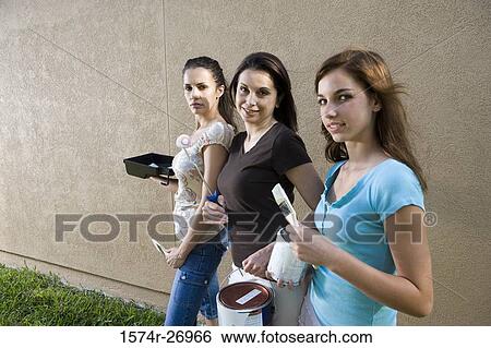 Portrait of a mother with her daughters with paint can and brushes standing by wall View Large Photo Image Stock Photograph - Portrait of a mother with her daughters with paint can and brushes standing by wall. Fotosearch