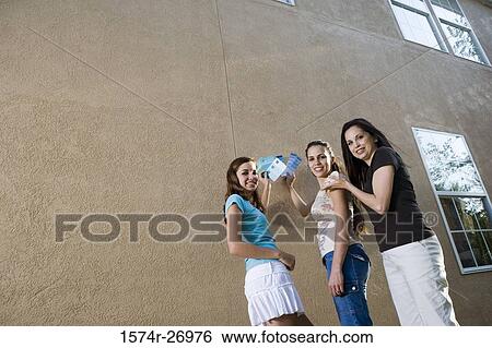 Stock Photograph - Portrait of a mother with her daughters holding color swatches against wall. Fotosearch