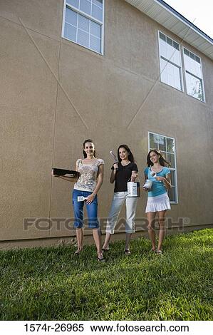 Portrait of a mother with her daughters with paint can and brushes standing by wall View Large Photo Image Stock Photography - Portrait of a mother with her daughters with paint can and brushes standing by wall. Fotosearch