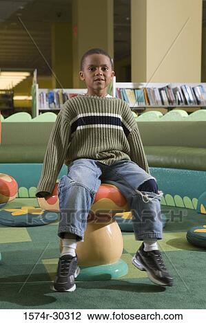 Portrait of a schoolboy sitting on stool in the library View Large Photo Image Stock Image - Portrait of a schoolboy sitting on stool in the library. Fotosearch