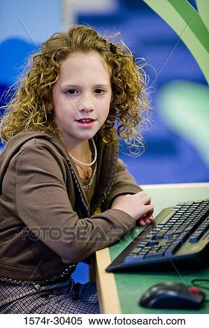 Portrait of a schoolgirl sitting by desk in the library View Large Photo Image Stock Photography - Portrait of a schoolgirl sitting by desk in the library. Fotosearch