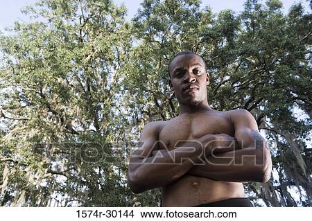 Picture - Portrait of a shirtless man standing with his arms crossed. Fotosearch