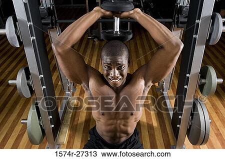 Portrait of a shirtless young man working out with dumbbells View Large Photo Image Stock Image - Portrait of a shirtless young man working out with dumbbells. Fotosearch